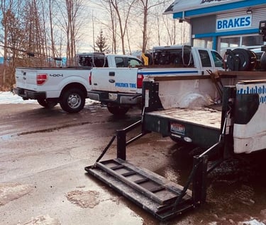 Service trucks parked outside a Premier Tire and brake repair shop in winter.