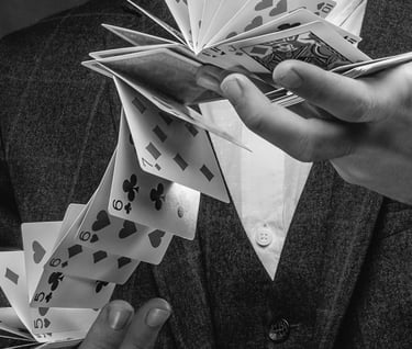 Las manos de un hombre manipulando una baraja en el aire, en gesto de un truco de magia