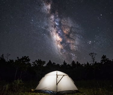 A lone tent pitched under a vast, clear dark charcoal sky filled with a Milky Way of stars. The tent is a soft off-white point of light in the wilderness. Global / Western forest clearing.