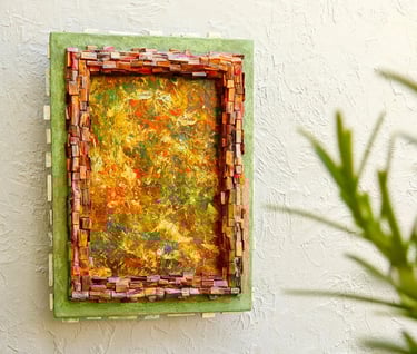 Abstraktes Bild mit Rahmen aus kleinen dunklen Holzscheiten und einem weiteren, grünen Betonrahmen