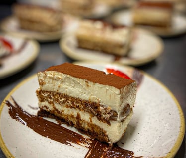 Tiramisu plated in a round plate with a chocolate cross painted