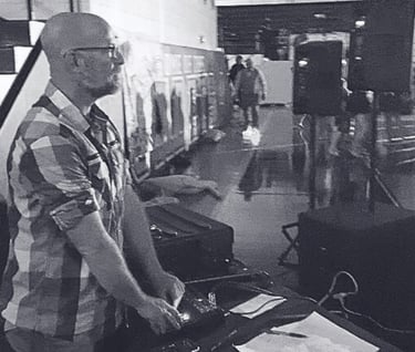 black and white image of man behind dj equipment