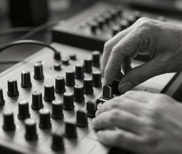 Close-up black and white photography of an artist's hands adjusting a modular synthesizer. Soft focus on the background, sharp details on the metal knobs and cables. Artistic and cinematic mood.