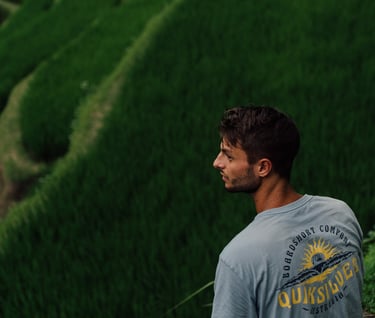 a man sitting on a ledge looking out over a rice field