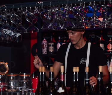 a bartender at a bar with wine glasses and wine glasses