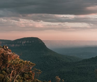 a person sitting on a mountain top with a view of the mountains