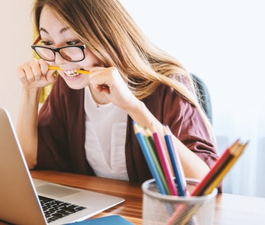 a woman sitting at a desk with a pencil and pencils