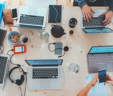 a group of people sitting at a table with laptops and cell phones