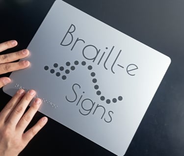 a person holding a sign that says braille signs