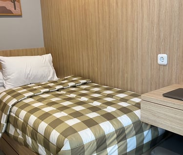 Kamar kos eksklusif Kos Si Bos Surabaya dengan single bed, meja belajar, lemari kayu, dan suasana modern minimalis