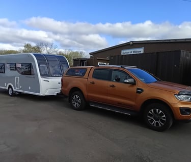 Orange Ford Ranger pickup truck towing a white Bailey Phoenix caravan at Duncan of Wishaw.