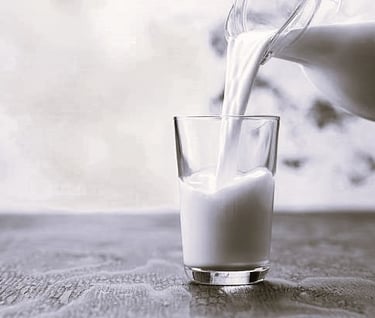 a pitcher of milk being poured into a glass