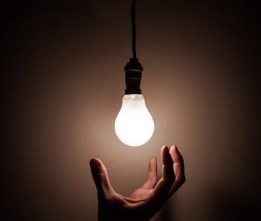 a person holding a light bulb in a dark room