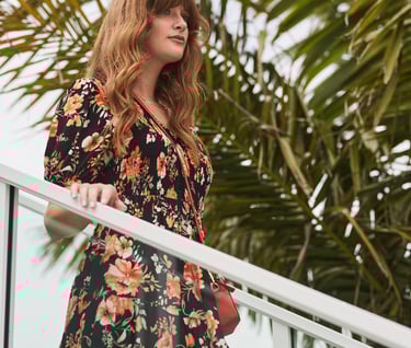 Fashion campaign photography - a woman in a floral dress standing on a balcony railing