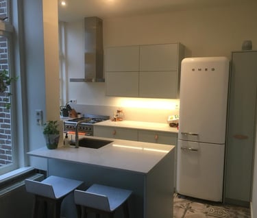 a kitchen with a refrigerator, refrigerator, and stool