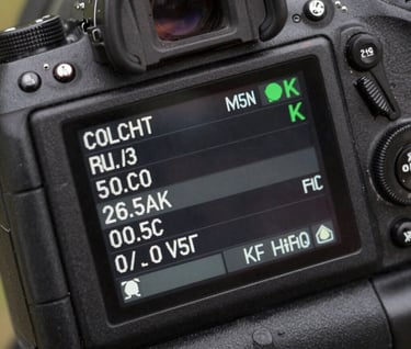 Detailed shot of a digital camera's rear LCD screen displaying a menu, extremely sharp, set against a charcoal gray camera body.