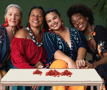 a group of women sitting on a couch with goji berries in front of them on table