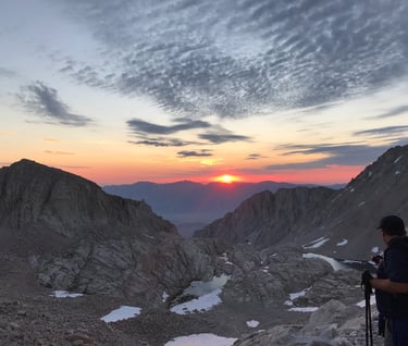 Sunrise from viewpoint on Mt Whitney with a hiker in foreground