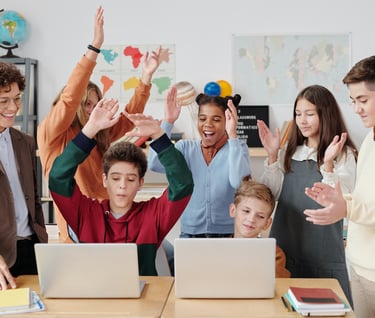 a group of people standing around a table with laptops