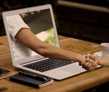 a man and woman shaking hands over a laptop
