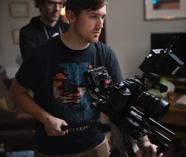 Film studio camera operator standing in front of a camera and holding another camera