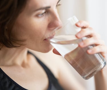 a woman drinking a glass of water for relief acidity  