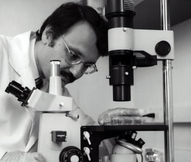 a man in a lab coat and glasses looking at a microscope study genetics