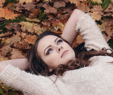 a woman laying on the ground in front of a pile of leaves