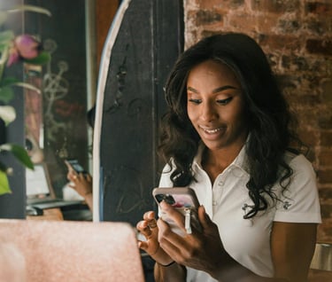 a woman sitting at a table with a laptop and a cell phone