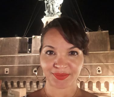 imagem da advogada Bianca Santos em frente a estátua de um anjo que fica no topo do castelo sant angelo em Roma na Itália.