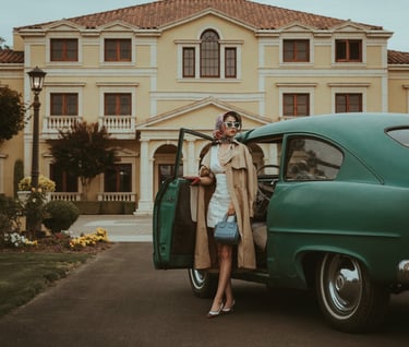 Woman coming out of a classic car parked in front of a mansion