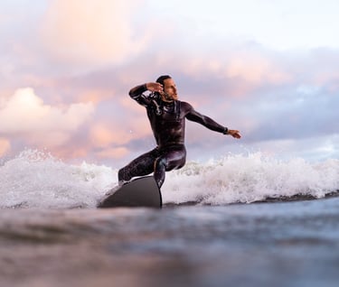 a man in a wetsuit surfing on a surfboard on sunset