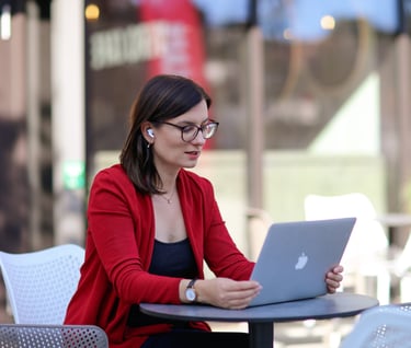 a woman sitting at a table with a laptop computer, talking