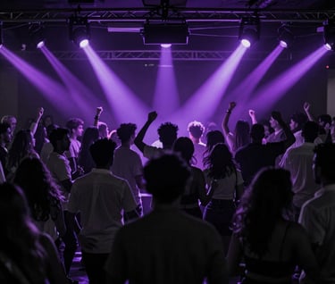 A high-contrast photography of a large audience dancing in a Spanish / Latin American nightclub. Silhouettes in obsidian and charcoal grey, illuminated by rhythmic flashes of electric violet light. High-end, premium party aesthetic.