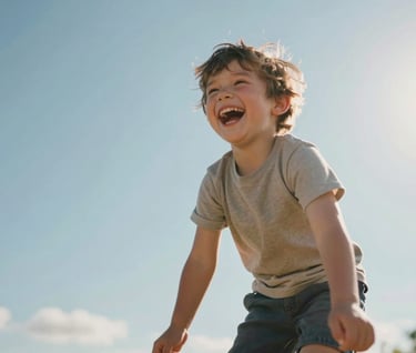 Candid shot of a small child laughing while being lifted into the air, sun flare in the corner, warm tones, authentic joy, cinematically framed against a soft blue sky.