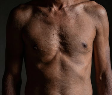 An artistic and intimate photograph of a human figure in a South American / Argentine setting. Low lighting creates a play of shadows in deep charcoal, treating the body as a territory of appearance where texture and light suggest something deeper and difficult to name.