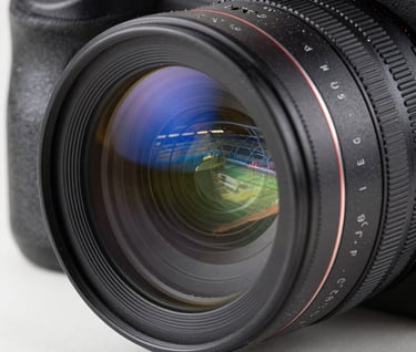 Extreme close-up of a high-tech camera lens with blue light reflections of a futuristic sports stadium, sleek dark metallic body, professional videography style, precision engineering aesthetic.