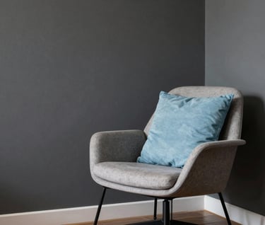 Interior photography of a minimalist Brazilian apartment, showing a corner with a dark gray wall and a sophisticated designer chair, a single baby blue cushion providing a pop of color, soft natural lighting.