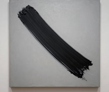 Photography of a minimalist painting with a single bold sweep of black paint across a light grey canvas, displayed with high-end museum lighting.