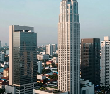 A high-angle shot of an urban landscape in a Southeast Asian / Indonesian business district. The architecture is modern and sleek, captured in the cool morning light with a color palette of Soft Sky Blue and Pale Mist White.