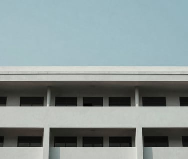 Minimalist architectural detail of a government building in Indonesia, showcasing clean lines and modern design. The composition is clean and focused, using a palette of pale mist and slate blue under a clear sky.