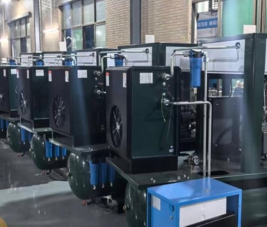 A row of industrial rotary screw air compressors with tanks in a manufacturing facility factory.