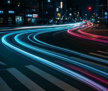 A long exposure night shot of a busy Korean urban intersection, with light trails of cars appearing as electric cyan and magenta ribbons against dark charcoal asphalt.