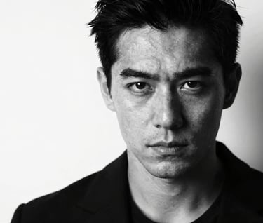 A striking black and white headshot portrait of an actor looking directly into the lens. Intense emotional depth. High contrast chiaroscuro lighting using deep blacks (#0F0F0F) and clean whites (#F5F5F5). International casting quality.