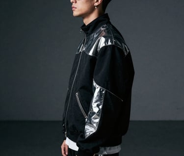 A portrait of a musician in profile, wearing high-fashion chrome-accented streetwear. The setting is a minimalist, dark gray industrial space in North America with cinematic lighting.