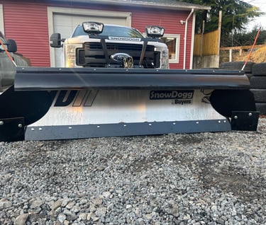 picture of the front of a white truck with a silver plow blade on it