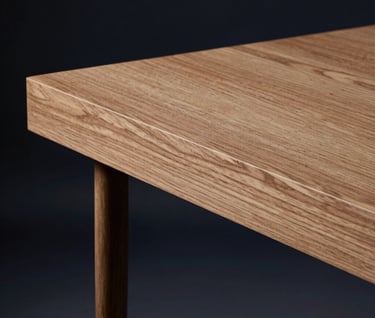 Side profile of a bespoke oak wood desk, focusing on the precision of the construction and the natural texture. Dark navy background, artistic lighting.