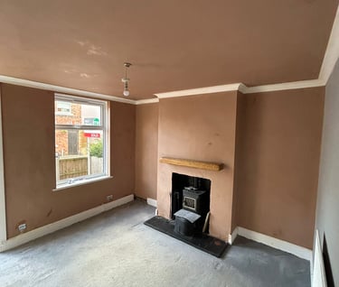 Empty living room with fresh brown plaster walls, a wood-burning stove, and grey carpet.