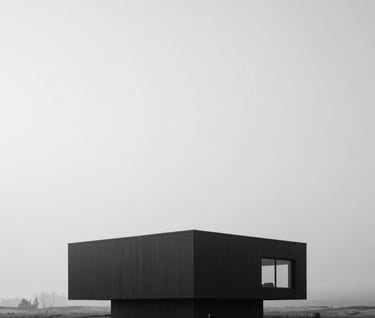 A wide, cinematic shot of a minimalist modernist building situated in a stark, misty North American / European landscape. The palette is strictly monochrome, with the dark structure contrasting against a soft white sky.