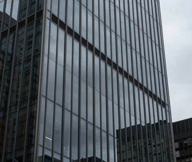 Architectural detail of a modern glass skyscraper in a North American / US downtown, reflecting a charcoal gray sky, clean lines and premium urban aesthetic.